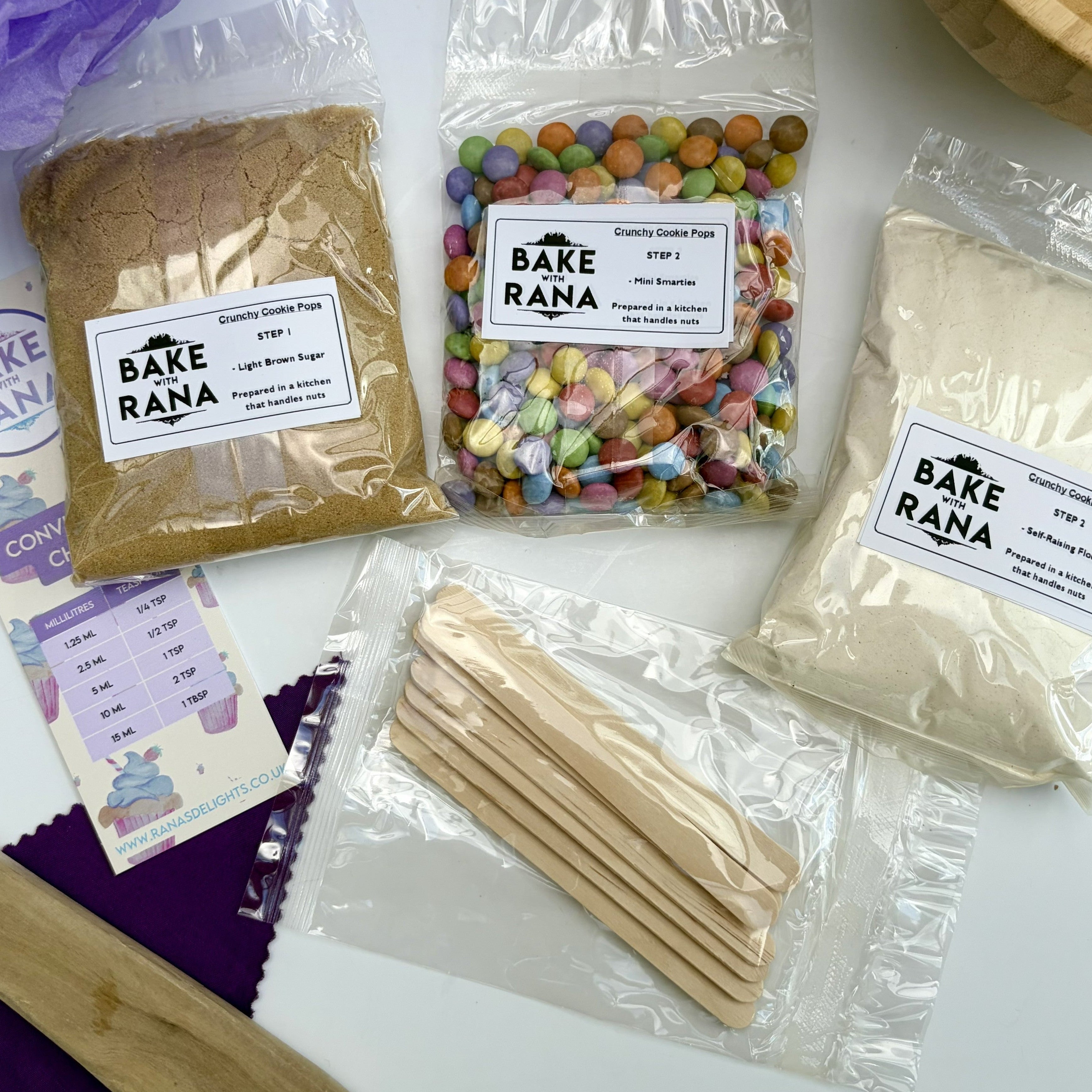 Bake With Rana product packaging on a white surface with bunting. 